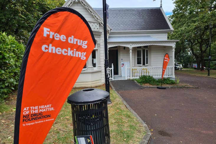 Sign saying free drug checking in front of caretaker's cottage