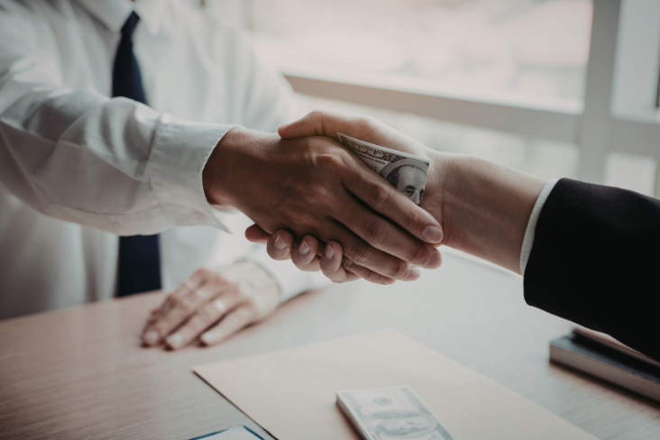 Handshake with a banknote hidden between the hands