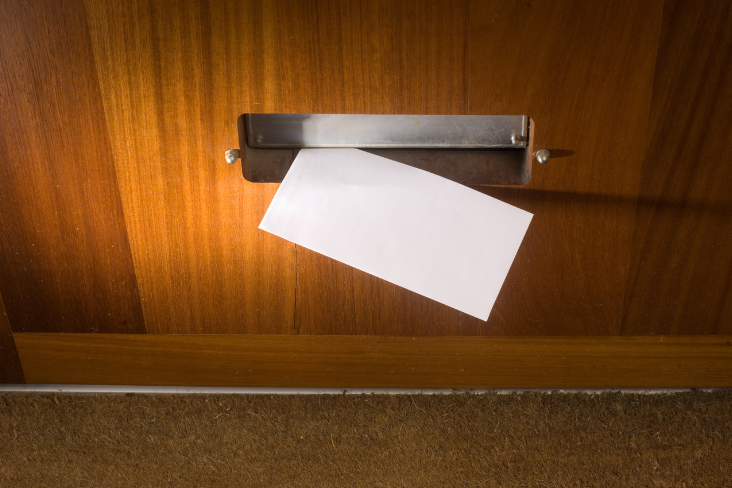 An envelope pushed through a door